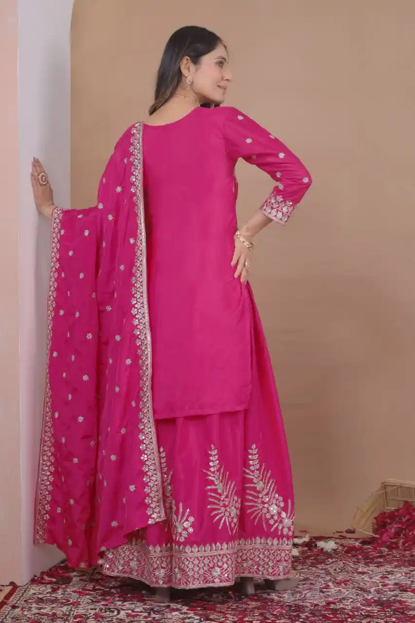 Woman wearing a pink traditional outfit with white embroidery against a beige background