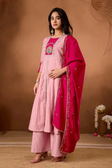 Woman wearing a pink traditional outfit with a red dupatta against a brown background