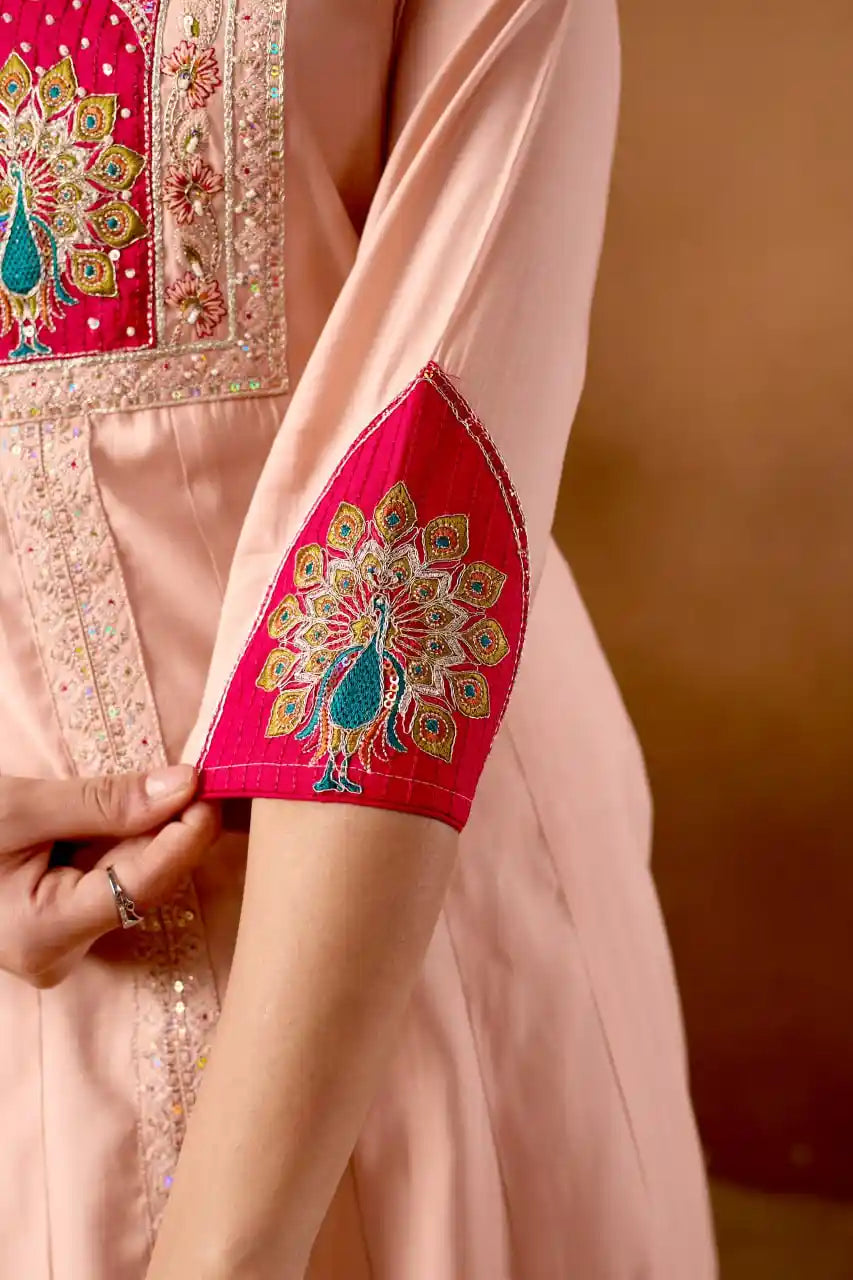 Close-up of a pink embroidered garment with intricate patterns on a brown background