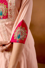Close-up of a pink embroidered garment with intricate patterns on a brown background