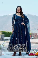 Woman in a dark blue traditional outfit with white patterns standing outdoors.