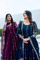 Two women in traditional outfits with embroidered designs outdoors.