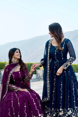 Two women in traditional outfits sitting outdoors with a mountainous background