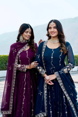 Two women in traditional attire standing outdoors with a scenic background.