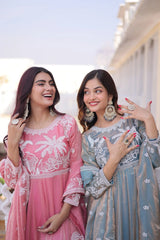 Two women in traditional outfits standing outdoors with a building in the background.
