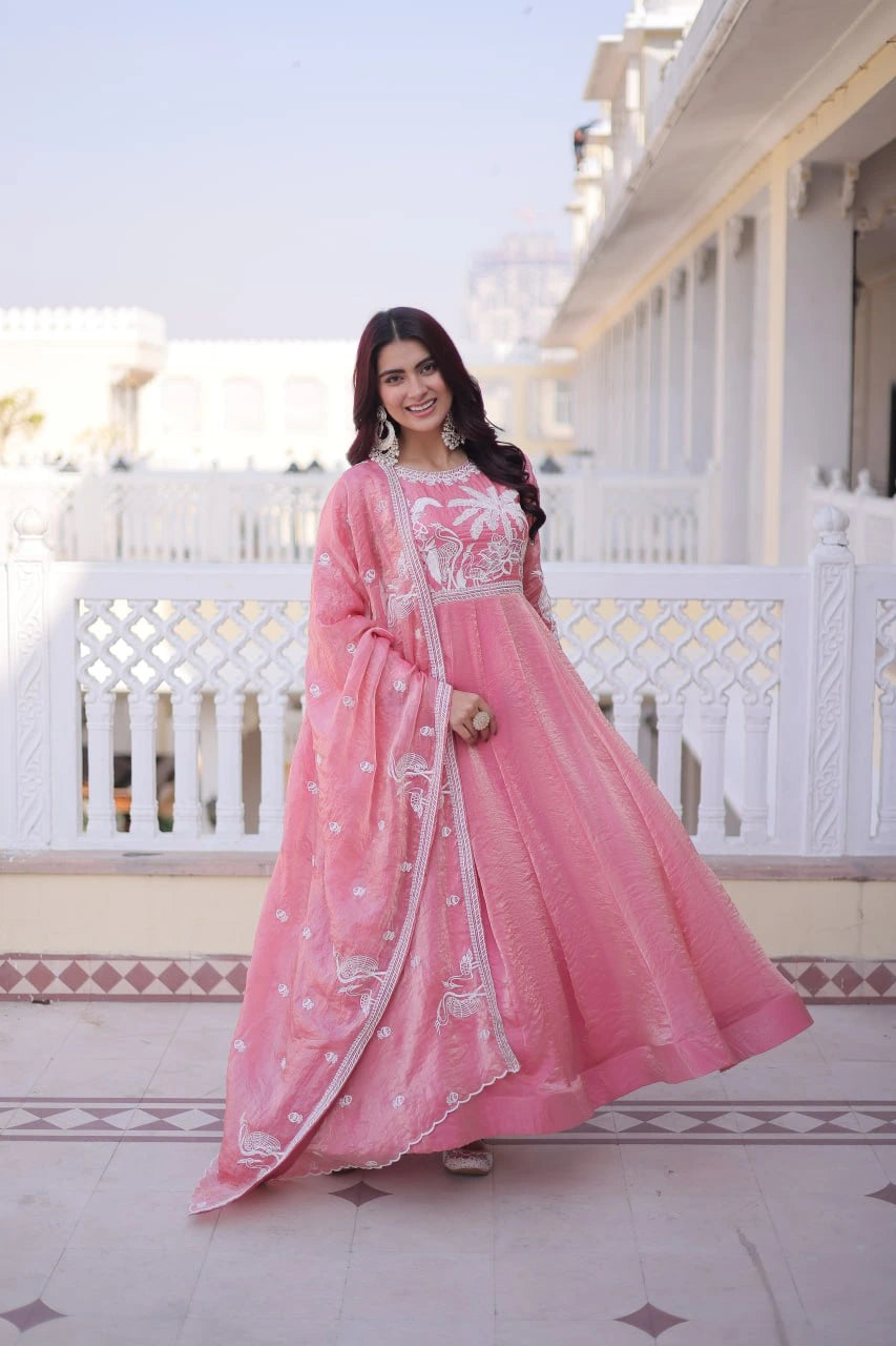 Woman in a pink traditional outfit standing on a balcony with white railings.