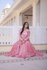 Woman in a pink traditional outfit sitting on a balcony with a white building in the background