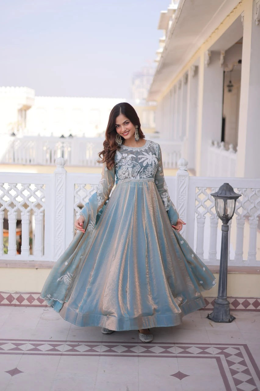 Woman in a long, light blue and white patterned dress standing on a balcony.