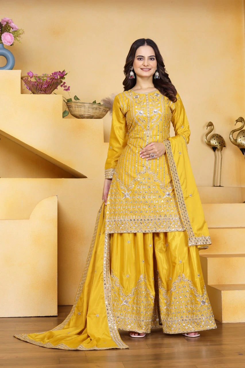 Woman in a yellow traditional outfit standing in a decorated room.
