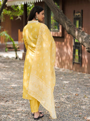 Woman in a yellow traditional outfit standing outdoors near a tree