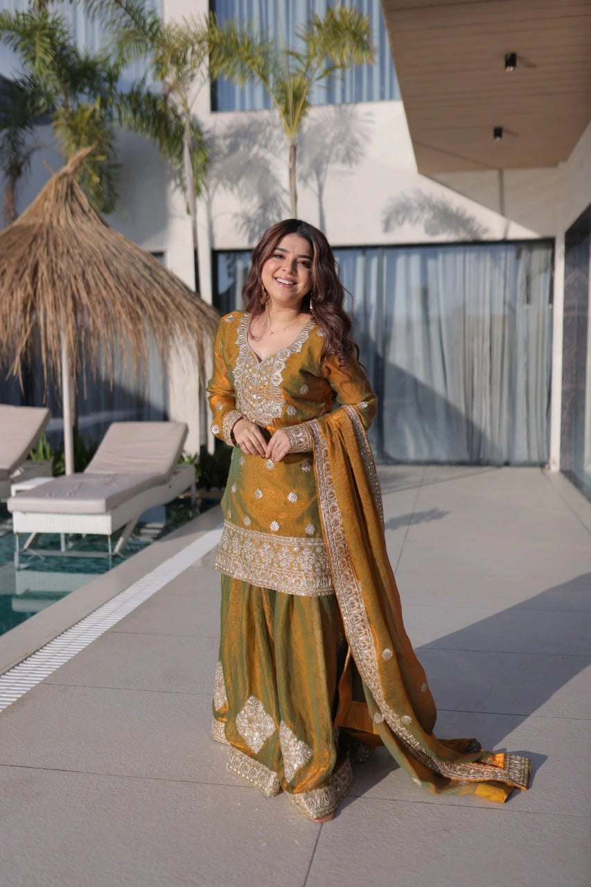Woman in traditional green and gold outfit standing by a poolside.