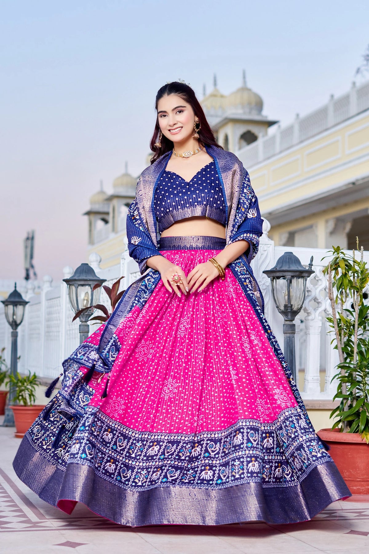 Woman in a traditional outfit with a pink and blue design, standing outdoors.
