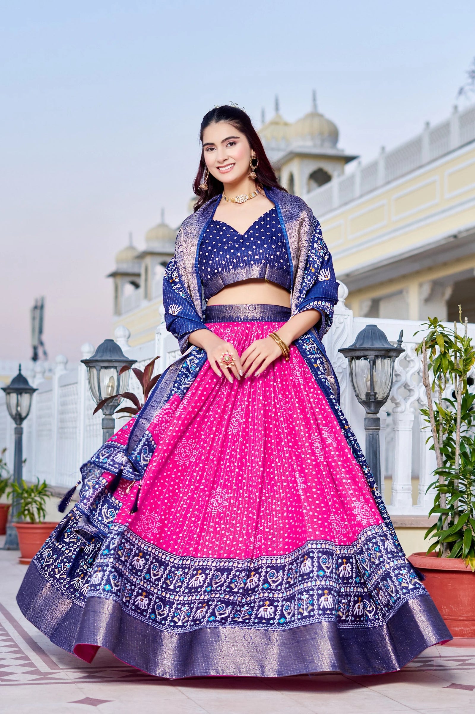 Woman in a traditional outfit with a pink and blue design, standing outdoors.