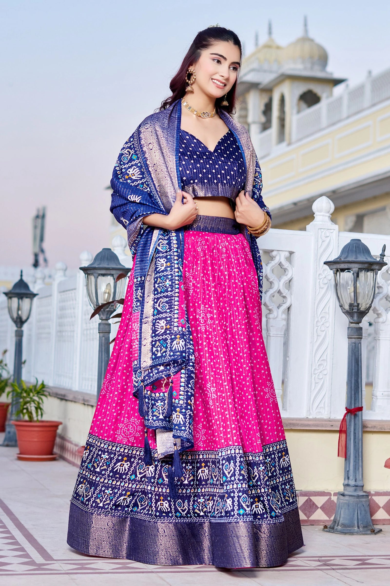 Woman in a traditional outfit with a blue and pink dress, standing outdoors.