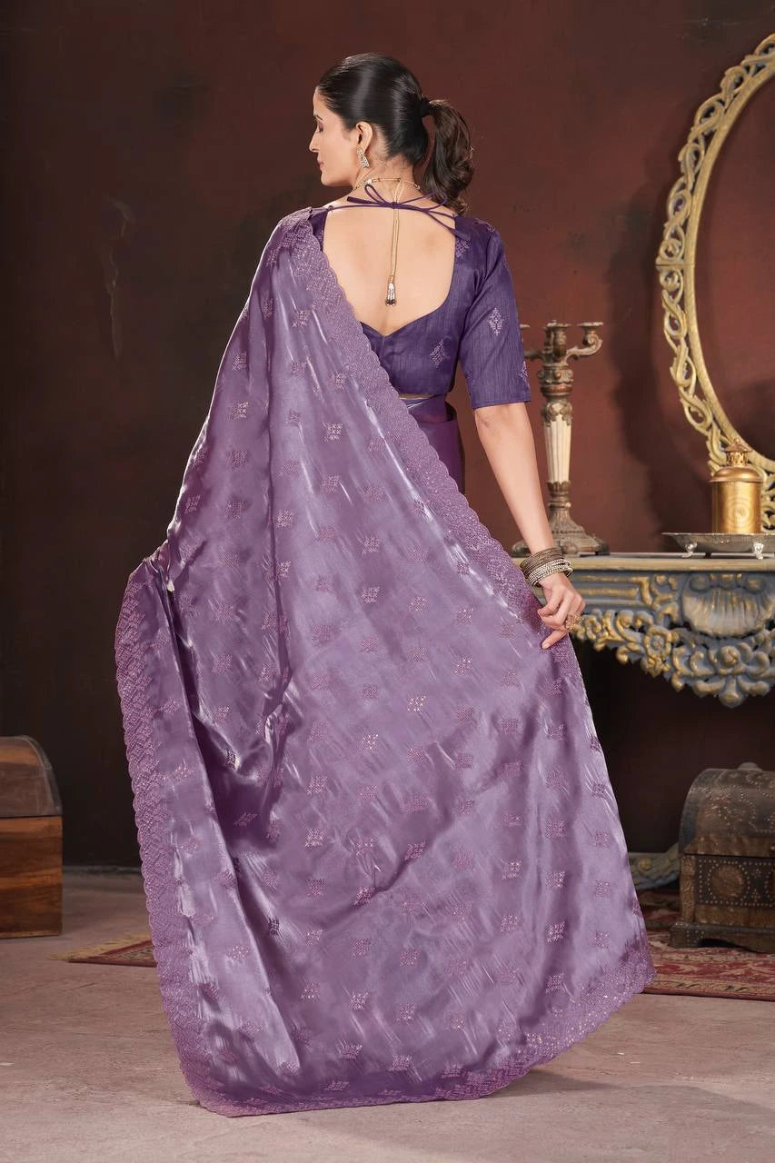 Woman wearing a purple saree in a room with decorative elements.