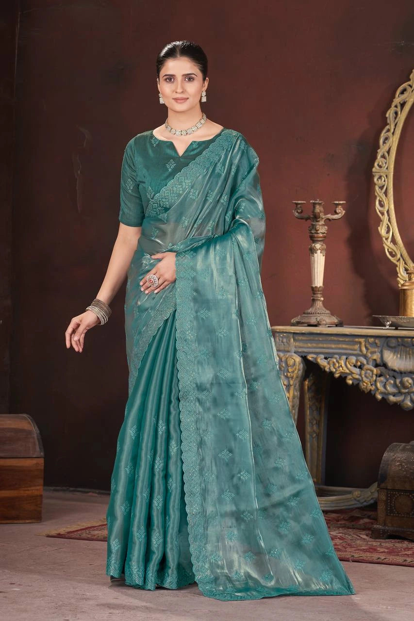 Woman wearing a teal saree with a dark background