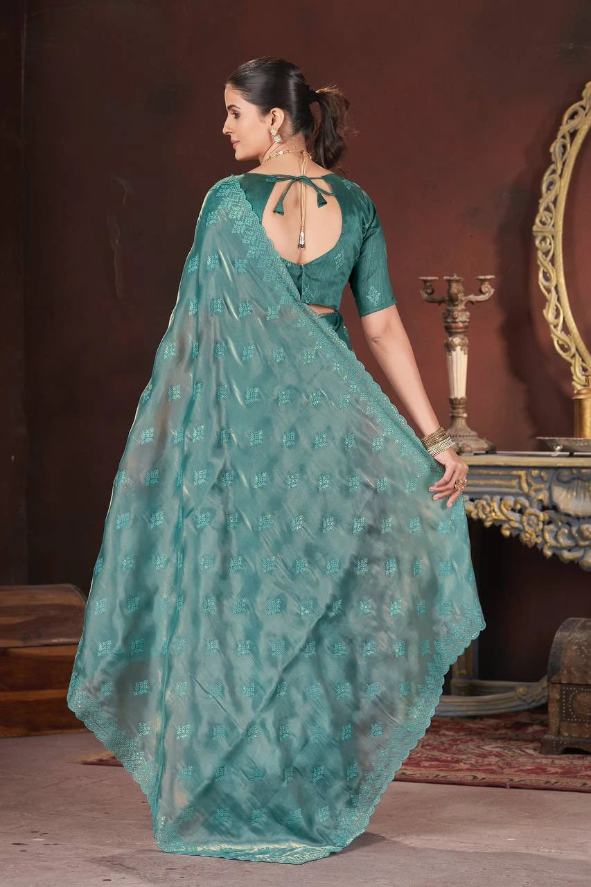 Woman in a teal saree with a matching blouse in an indoor setting.