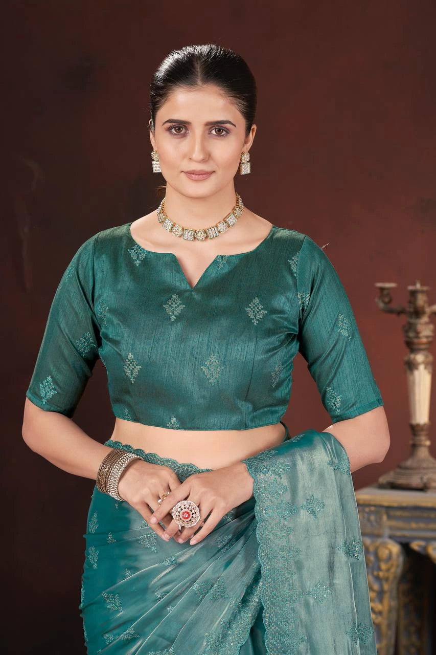 Woman wearing a green saree with a matching blouse against a dark background