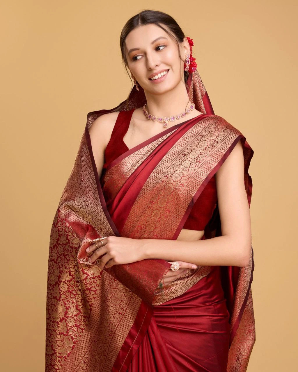 Woman wearing a red saree with gold border on a beige background