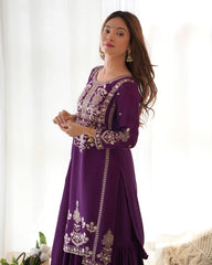 Woman wearing a purple embroidered dress against a white curtain background