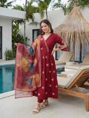 Woman in a red traditional outfit with a floral dupatta by a poolside.