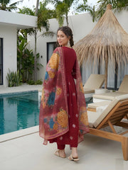 Woman in a red traditional outfit with floral patterns by a poolside.