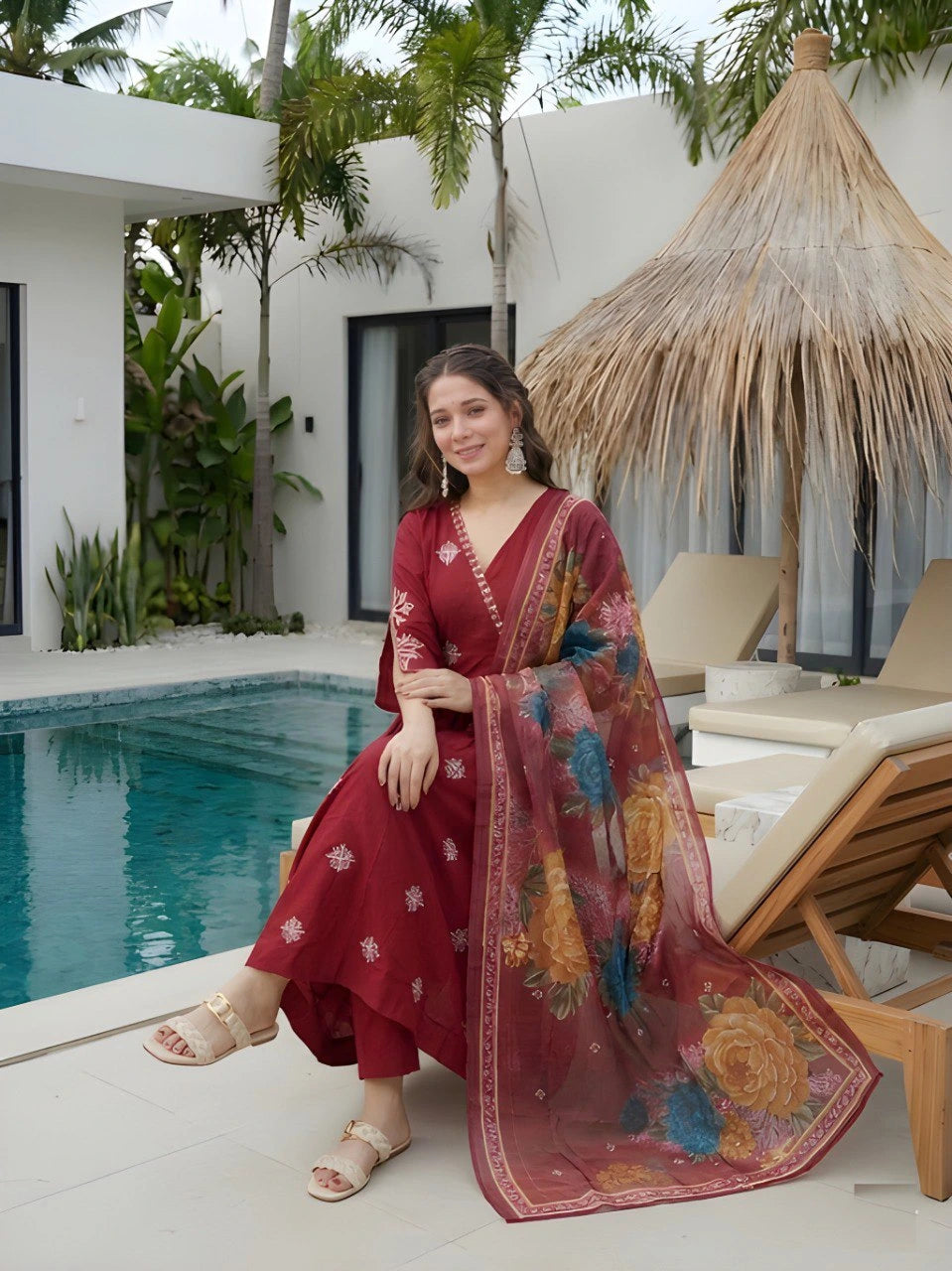 Woman in a red dress with a floral scarf by a poolside