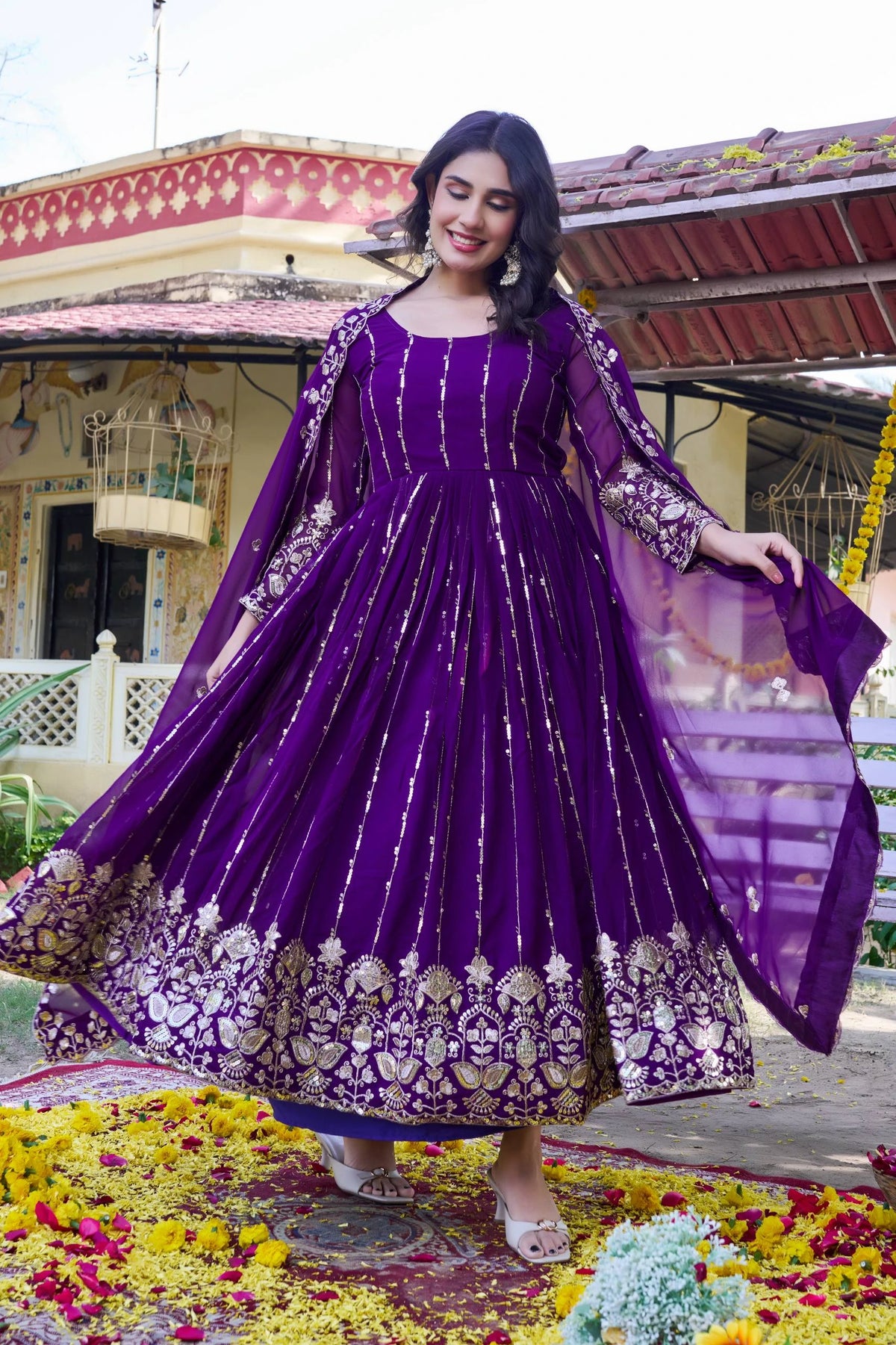 Woman in a purple traditional outfit with floral decorations in the background