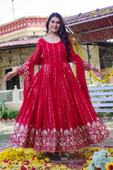 Woman in a red traditional outfit standing in front of a decorated building.