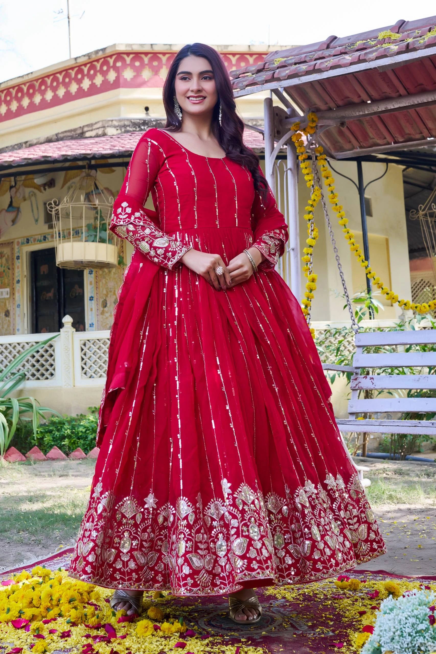 Woman in a red traditional outfit standing in front of a decorated building.
