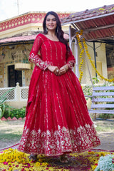 Woman in a red traditional outfit standing in front of a decorated building.