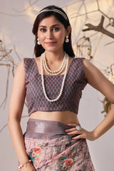 Woman wearing a patterned blouse and skirt with jewelry against a neutral background