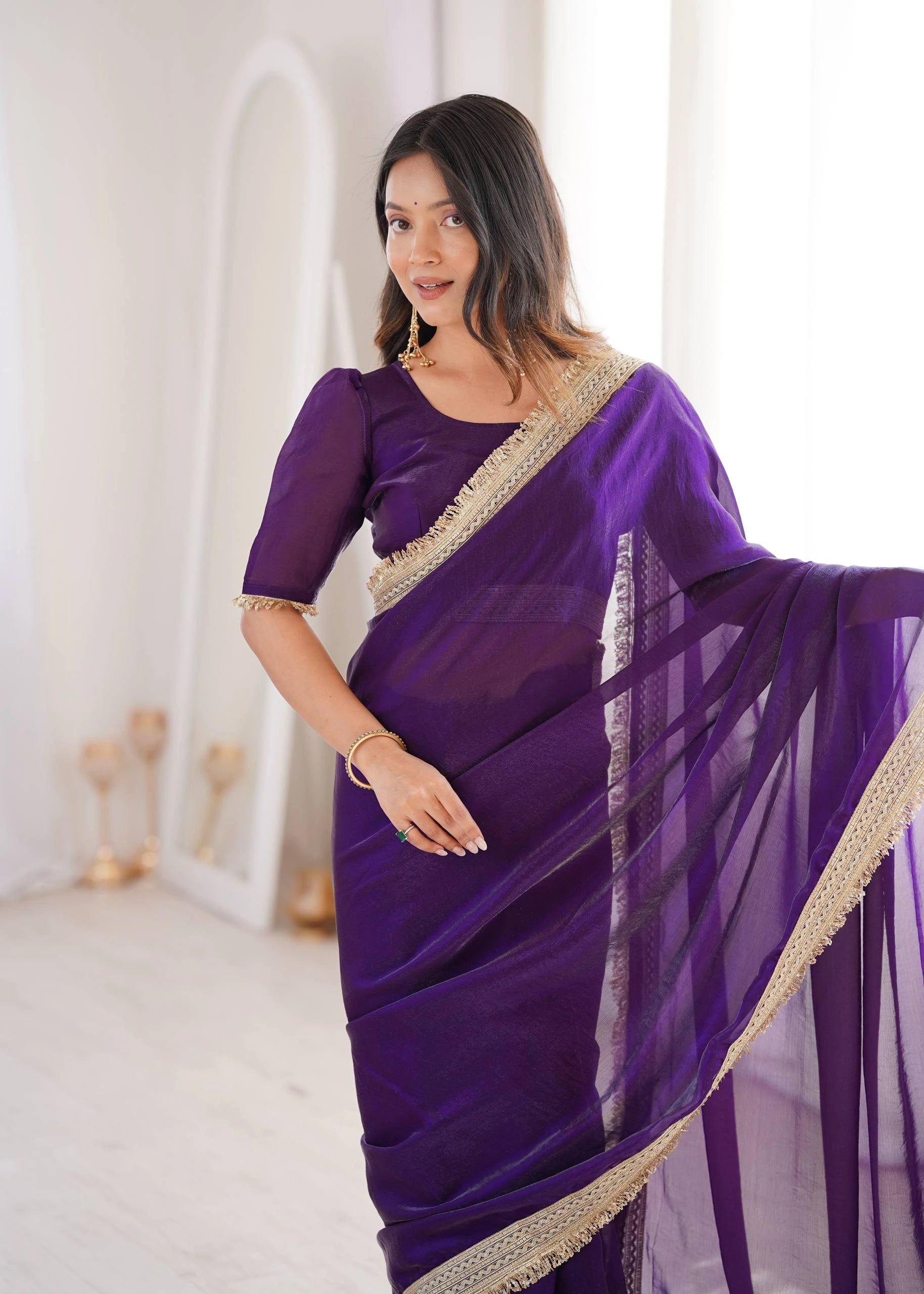 Woman wearing a purple saree with gold border in a bright room