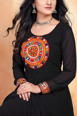 Woman wearing a black outfit with colorful embroidery on a beige background