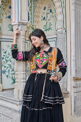 Woman in traditional outfit with colorful embroidery standing in front of an ornate wall.