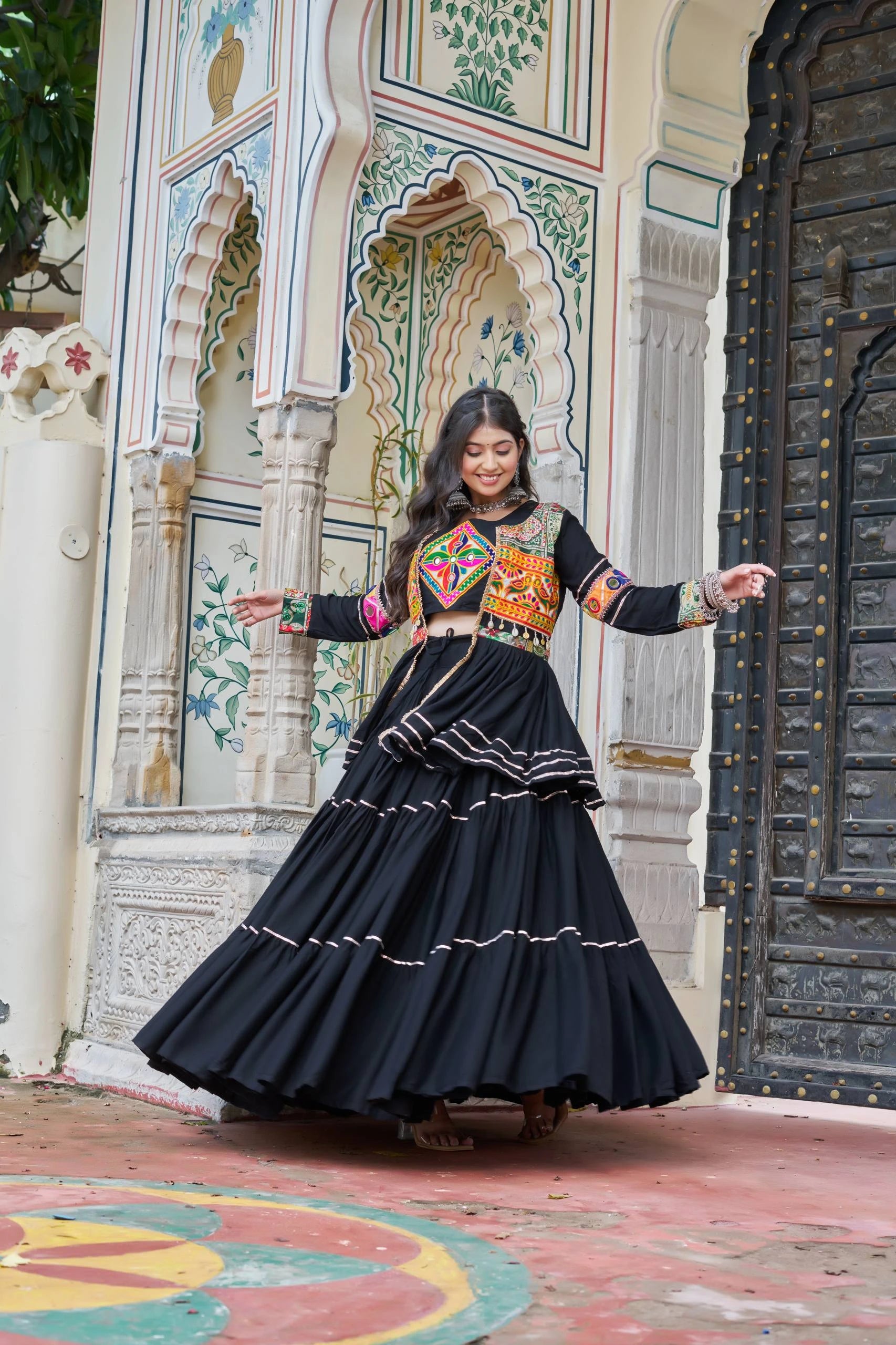 Woman in traditional outfit standing in front of a decorative architectural background
