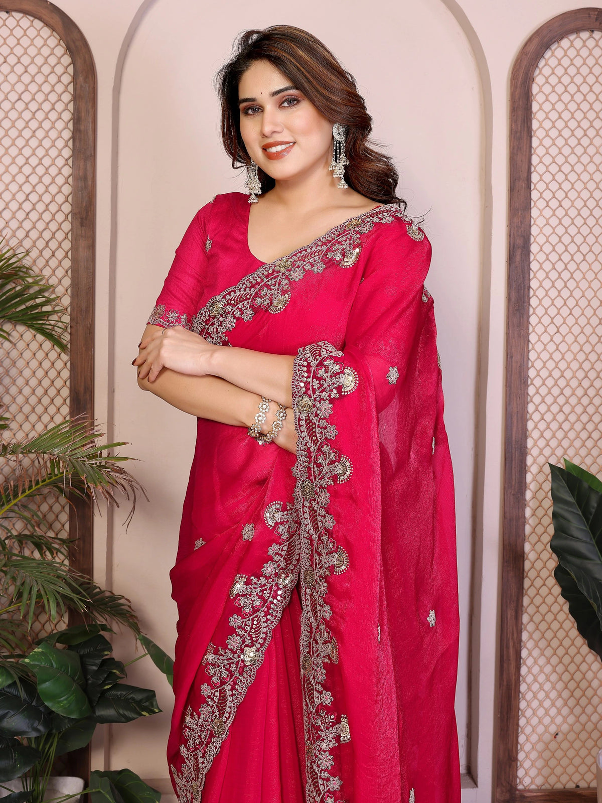 Woman wearing a red saree with silver embroidery against a neutral background