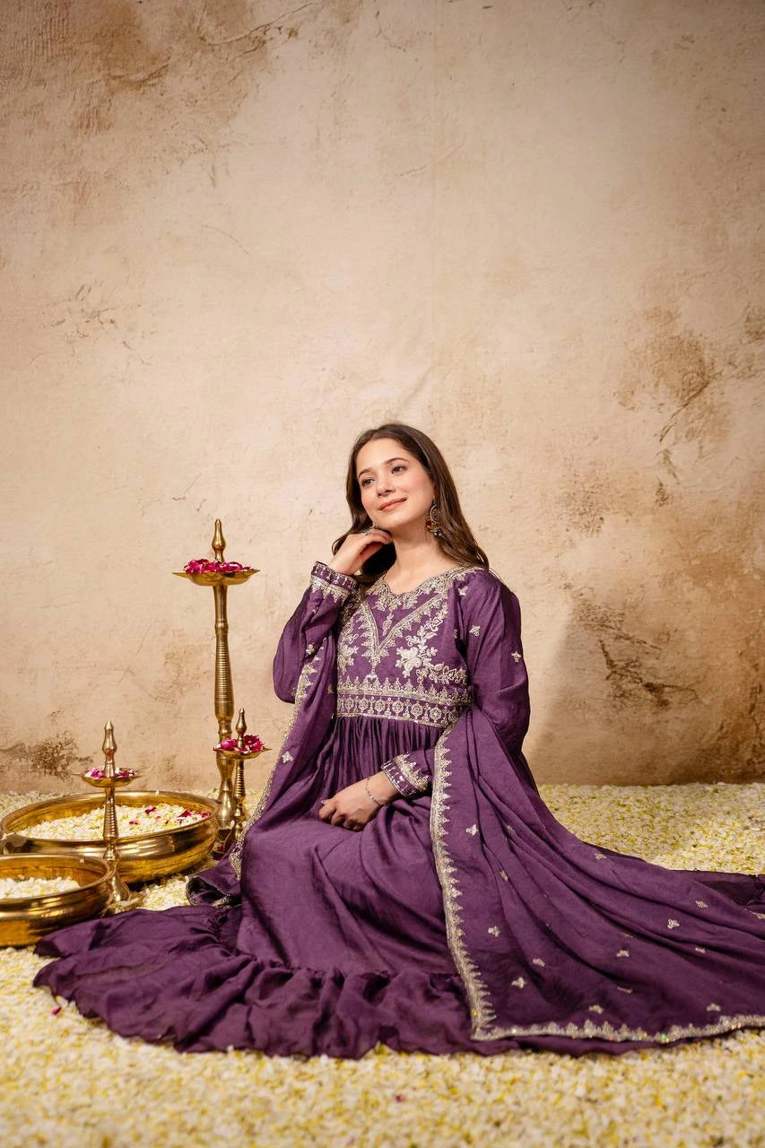 Woman in a purple traditional outfit sitting on a textured floor with decorative elements.