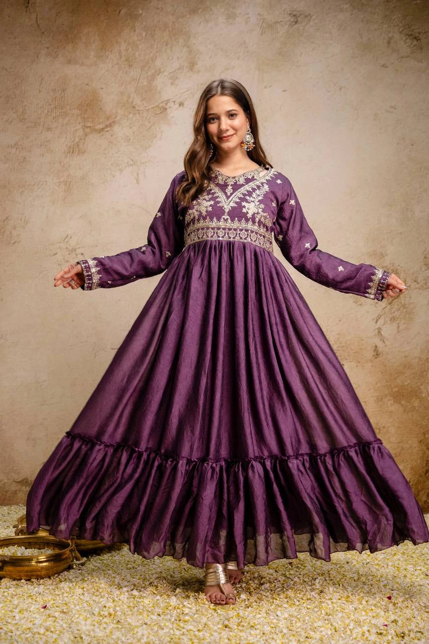Woman wearing a purple traditional dress with intricate patterns on a textured beige background
