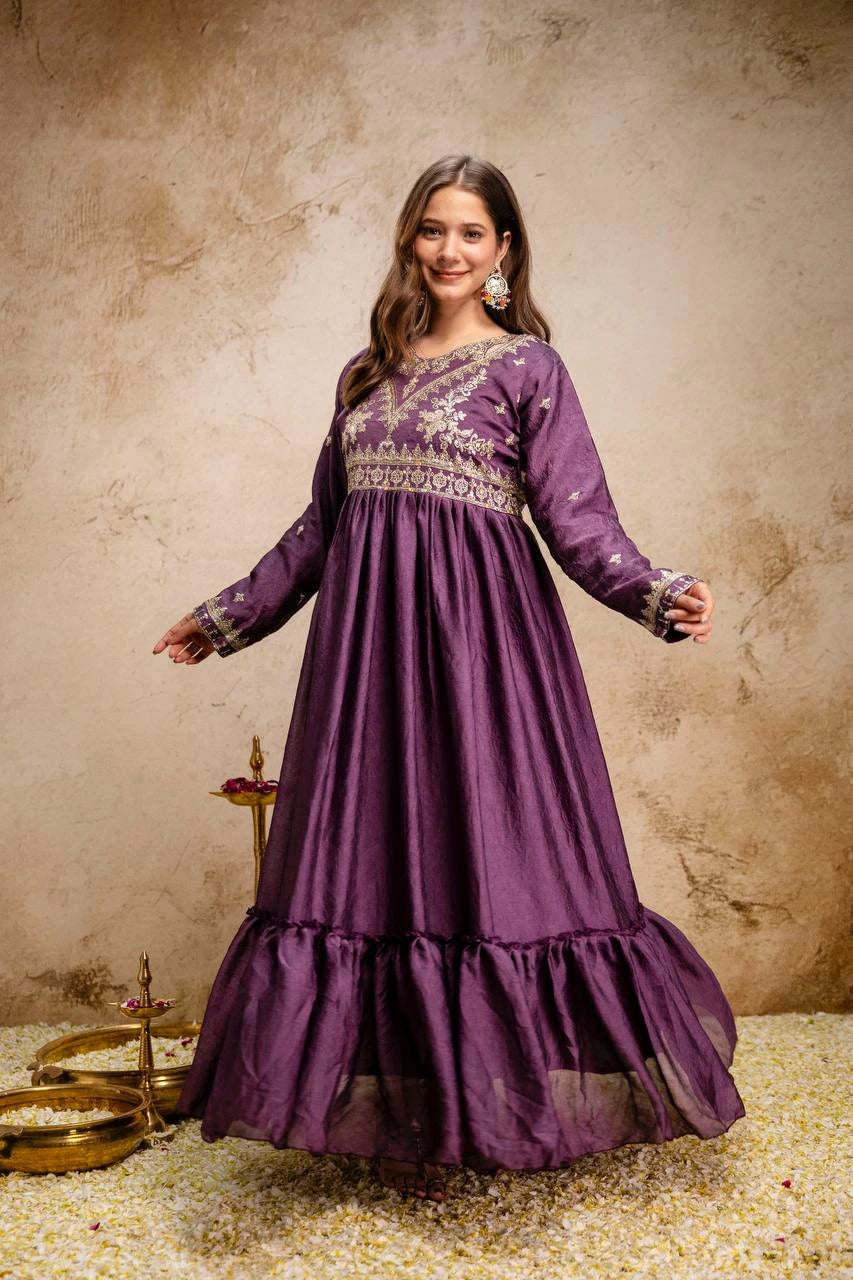 Woman wearing a purple dress with intricate patterns on a textured beige background