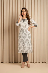 Woman wearing a white floral kurta with black pants against a beige curtain background