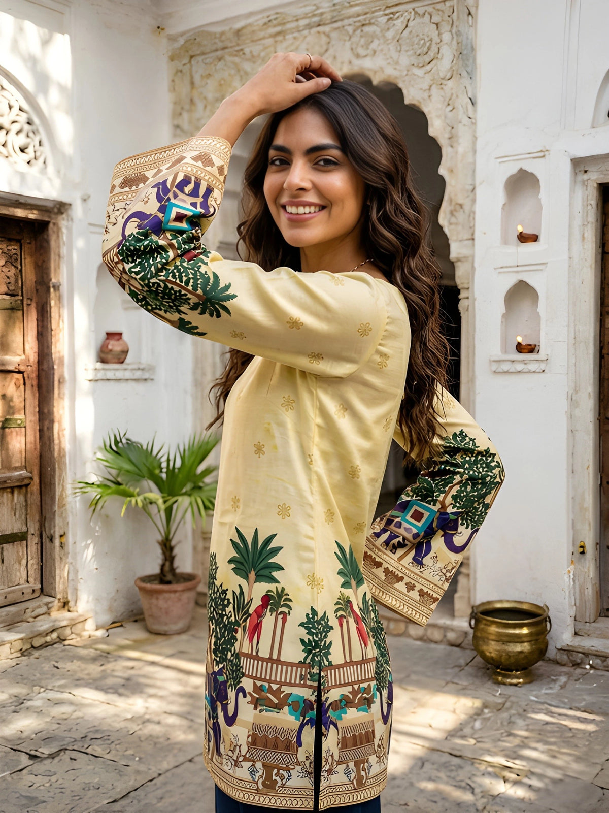 Side view of yellow Kalamkari cotton short kurti showing vibrant elephant and tree print on sleeves, Rajasthani courtyard background