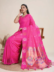 A woman models a luxurious Rani Pink Soft Silk Saree. The saree features scattered metallic motifs and a wide pallu in contrasting copper/rose gold, richly woven with multi-colored peacock and floral designs. She wears a matching pink sleeveless blouse and heavy gold Kundan jewelry, posing indoors.