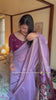 A woman models a soft Lavender Muga Silk Saree with subtle Resham weaving. The pallu dramatically transitions to a deep purple color, featuring intricate blue and purple peacock Resham threadwork. She wears a dark purple blouse and a gold Kundan necklace.