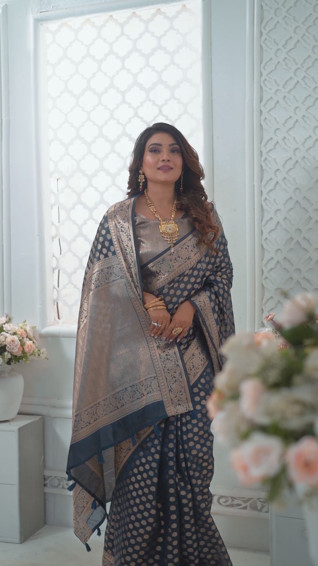 Woman wearing a silver and blue saree with a white background