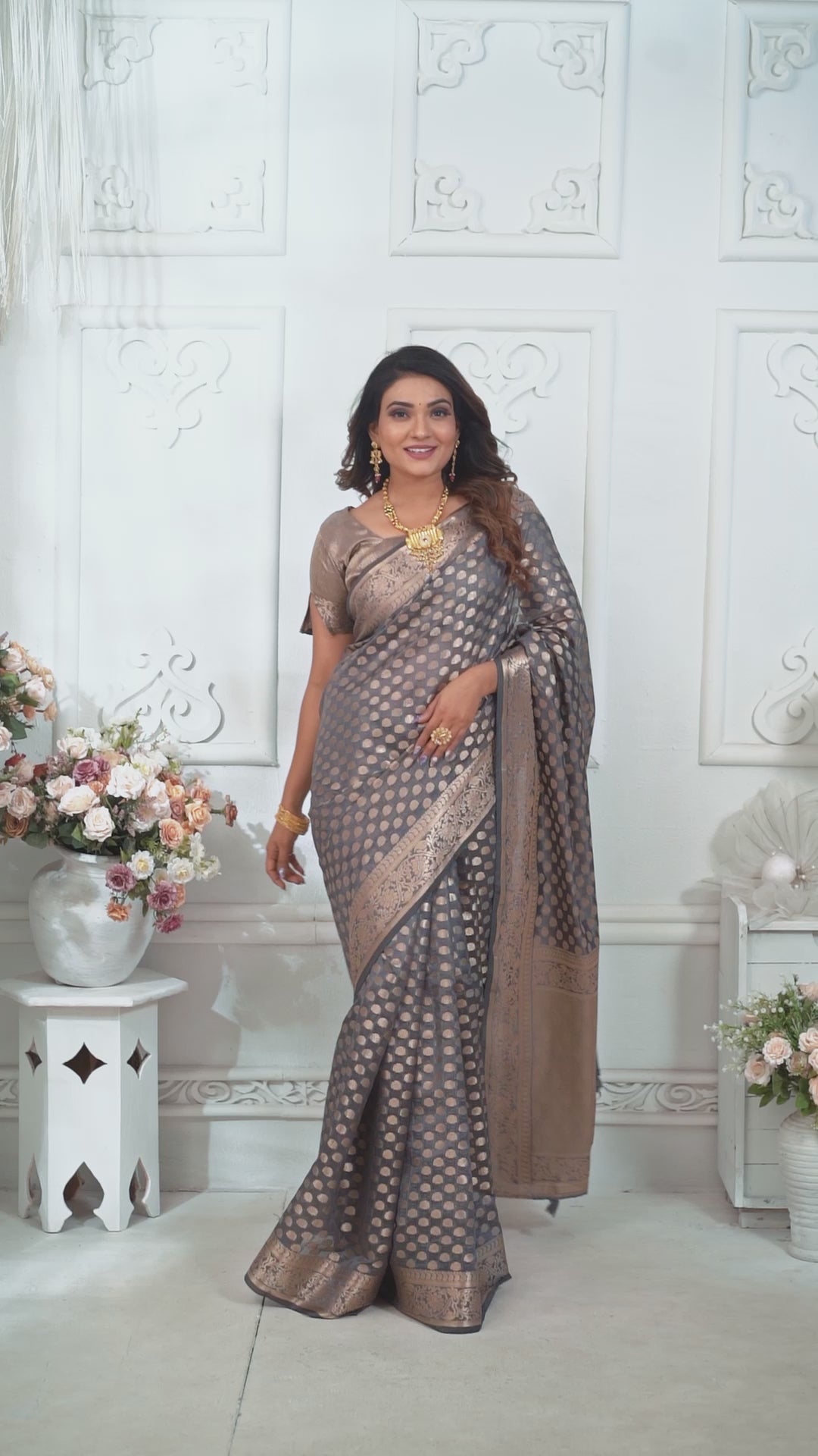 Woman wearing a traditional saree with jewelry against a white background
