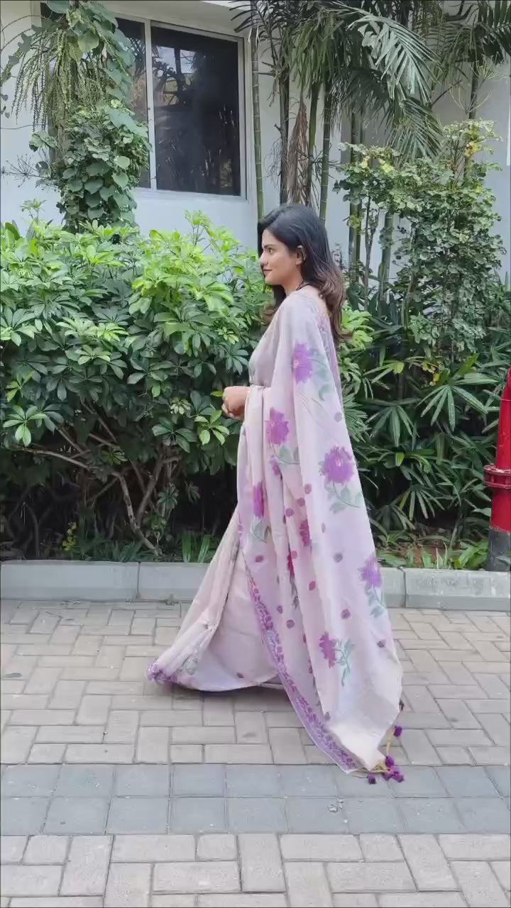 Woman in elegant purple resham weaving saree with floral motifs near plants