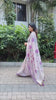 Woman in elegant purple resham weaving saree with floral motifs near plants