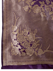 A woman models a luxurious Deep Purple Soft Kanjivaram Silk Saree. The saree features striking large floral and scattered motifs woven in metallic gold Zari on the body and wide pallu. She wears a matching purple sleeveless blouse and accessorizes with a heavy gold Kundan choker necklace and earrings.