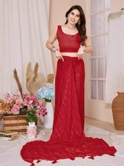 A woman models a vibrant Crimson Red Rimzim Silk Saree. The sheer fabric features prominent vertical stripes and scattered embellishments of fine metallic (silver) threadwork. She wears a matching sleeveless red blouse and accessorizes with chunky oxidized silver jewelry, including a layered necklace and a wide cuff bangle, posing indoors.